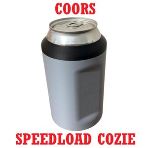 May include: A gray and black Speedload Cozie with the word "COORS" in red at the top. The cozie is designed to hold a can. The words "SPEEDLOAD COZIE" are printed in red at the bottom.