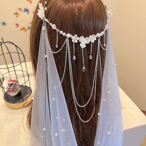 K&ouml;nnte beinhalten: Ein wei&szlig;er Braut Schleier mit Perlen Akzenten und einem silbernen Ketten Kopfschmuck verziert mit wei&szlig;en Blumen und Kristall Tropfen.