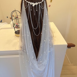 K&ouml;nnte beinhalten: Ein wei&szlig;er Braut Schleier mit Perlenbesatz und einem silbernen Ketten- und Blumenhaarschmuck.