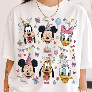 May include: White t-shirt featuring colorful cartoon character faces, including Mickey Mouse, Minnie Mouse, and Donald Duck, with birthday party decorations. The design includes cupcakes, balloons, and the text "Daisy Duck" and "Minnie Mouse XOXO".