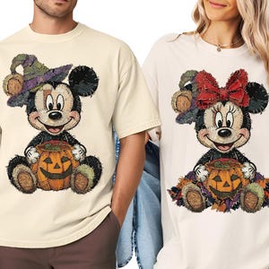 Puede incluir: Dos camisetas de color crema con un gráfico estilo patchwork de un personaje de ratón de dibujos animados. La camiseta izquierda muestra un ratón con sombrero de bruja y calabaza, la derecha un ratón con lazo rojo y una calabaza.