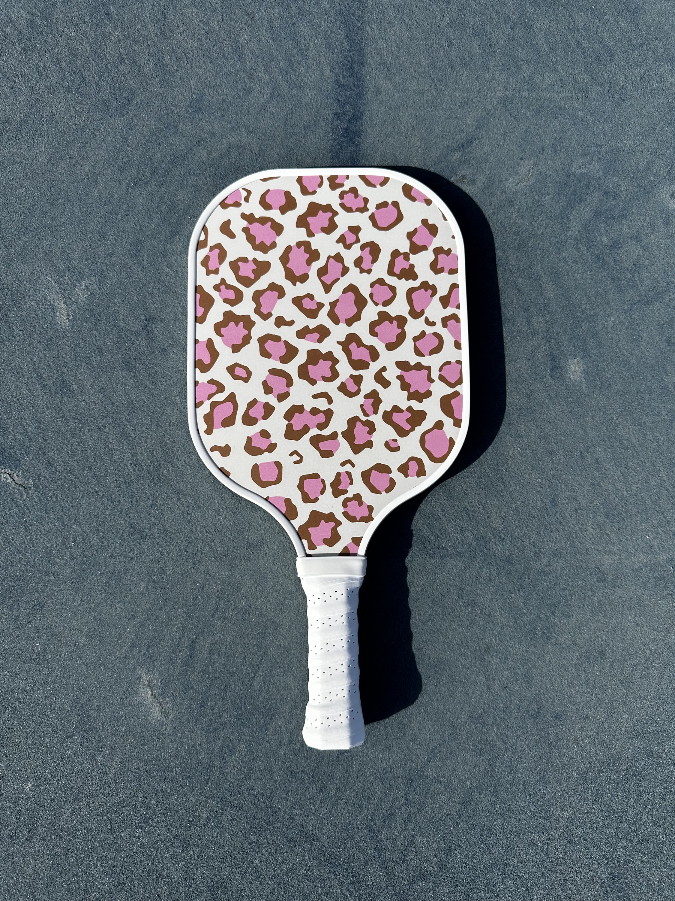 May include: A white pickleball paddle with a pink and brown leopard print design.