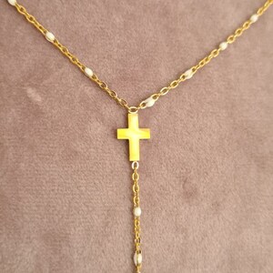 Peut inclure: Un collier en cha&icirc;ne dor&eacute;e avec des perles blanches et deux pendentifs en forme de croix dor&eacute;s.