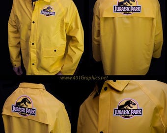 May include: A yellow raincoat with a black Jurassic Park logo on the back and a smaller logo on the left chest. The logo features a dinosaur silhouette.