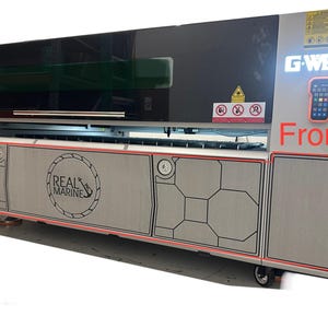 Op de afbeelding: Een grote industriële lasersnijder met een grijze en zwarte buitenkant. De machine heeft een bedieningspaneel en het woord "Front" in het rood. Op het voorpaneel staat het logo "REAL MARINE".