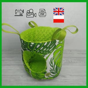 Può includere: Accessorio per animali domestici in tessuto verde e bianco con un motivo a foglie tropicali. L'interno è in tessuto verde strutturato. Ha due manici verdi e un'apertura circolare. L'accessorio è progettato per essere appeso.