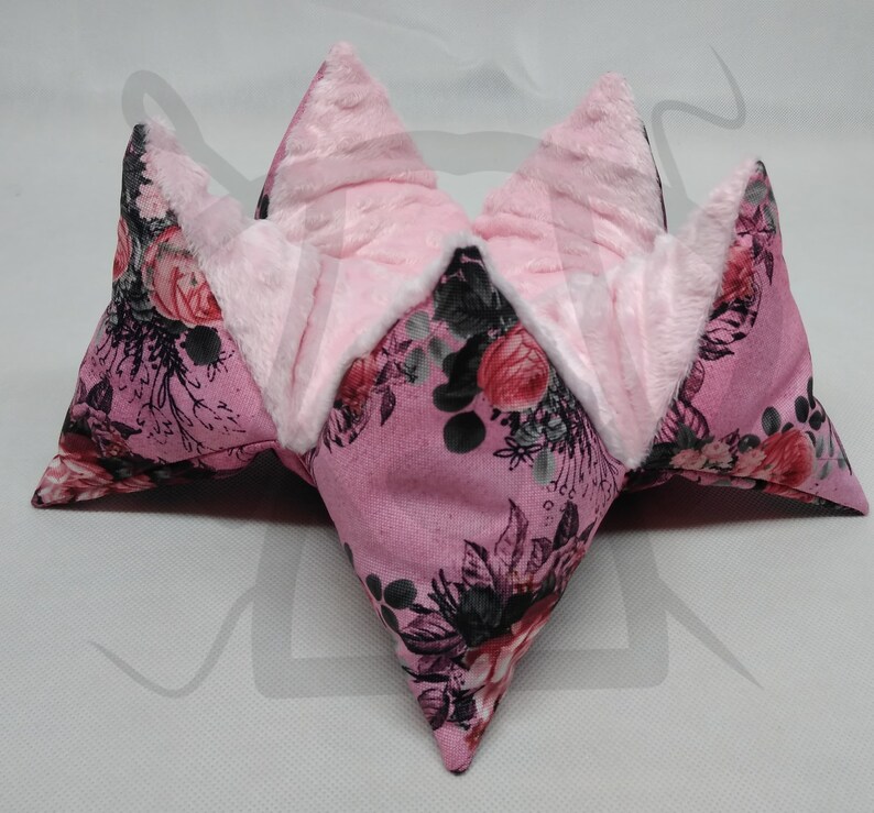 May include: A pink floral fabric storage basket with a soft white lining. The basket is folded into a star shape.