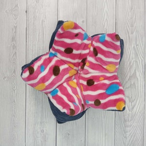May include: A pink and white star-shaped pillow with brown and blue polka dots and stripes. The pillow is made of soft, plush fabric.