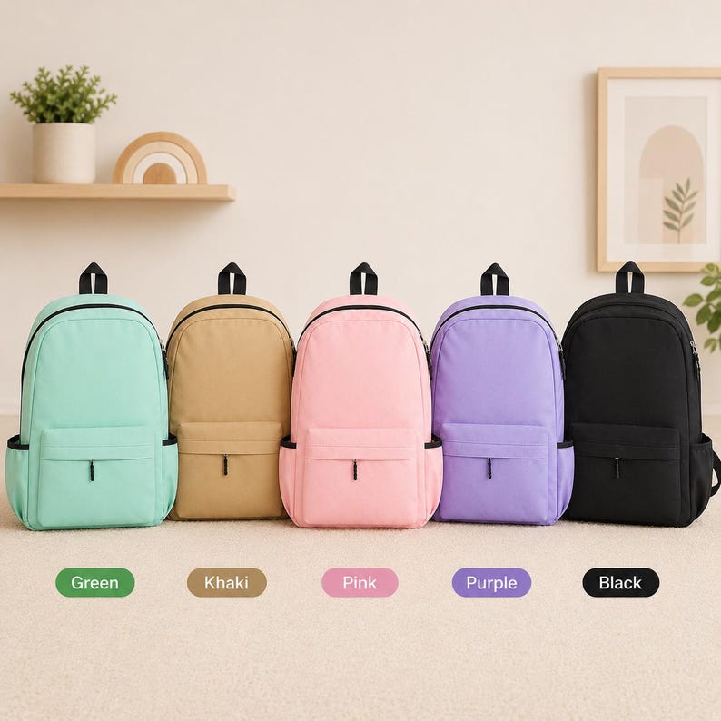 May include: Five backpacks in a row, each featuring a main compartment, a front zippered pocket, and side pockets. The backpacks are available in five distinct solid colors: mint green, khaki, light pink, lavender purple, and solid black.