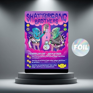 May include: A collectible card with the text "SHATTERGANG BROTHERS" in pink and blue. The card shows two goblin-like creatures with blue and green skin, holding vials and a potion. A circular sticker with the word "FOIL" is visible.