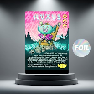 Puede incluir: Una carta coleccionable con un rey duende de dibujos animados en un trono, con el nombre "MUXUS" y "Goblin Grandee" en la parte superior. La tarjeta tiene un esquema de color rosa y verde azulado e incluye texto del juego y una pegatina "FOIL".