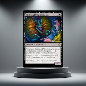 May include: A black trading card with a Spitting Dilophosaurus illustration. The card shows a green dinosaur with a colourful frill spitting at a person. Text includes "Spitting Dilophosaurus" and game instructions. The card is displayed on a grey pedestal.