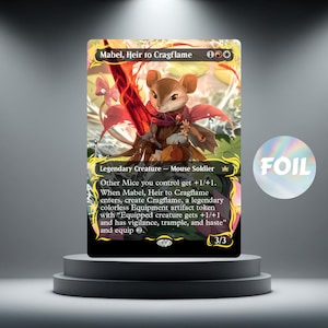 May include: A Magic: The Gathering card depicting "Mabel, Heir to Cragflame," a mouse soldier with a red sword. The card has a foil finish and is displayed on a tiered platform. The card text includes abilities and stats.
