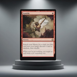 Peut inclure: Une carte rouge Magic: The Gathering intitulée "Gamble". La carte présente une illustration d'une créature dans une pose dynamique sur un fond nuageux. Le texte de la carte décrit une action de sorcellerie. La carte est présentée sur un piédestal gris.