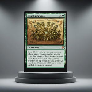 May include: A green "Doubling Season" card with an illustration of a multi-headed creature. The card includes text detailing its enchantment effect. The card is presented on a grey, tiered pedestal.