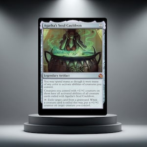 May include: A Magic: The Gathering card, "Agatha's Soul Cauldron," displayed on a pedestal. The card features a witch stirring a cauldron with green mist. The card text is visible, including "Legendary Artifact."