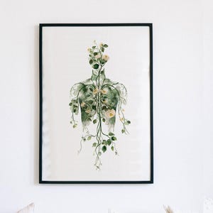 May include: A framed art print featuring a botanical illustration of a human form filled with flowers and vines. The artwork is in shades of green and white, with a black frame. The print is displayed on a white wall.