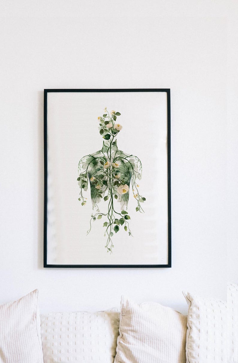 May include: A framed art print featuring a botanical illustration of a human form filled with flowers and vines. The artwork is in shades of green and white, with a black frame. The print is displayed on a white wall.