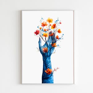 Puede incluir: Impresión artística en acuarela que representa una mano azul con ramas y flores naranjas y amarillas. La obra de arte está enmarcada en un marco plateado sobre un fondo blanco. El diseño floral añade un toque de naturaleza.