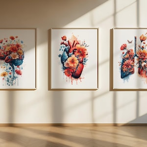 Könnte beinhalten: Drei gerahmte Aquarelldrucke, die menschliche Anatomie mit Blumen zeigen. Die Kunstwerke zeigen ein Gehirn, ein Herz und eine Lunge, jeweils mit bunten Blüten in Orange, Rot und Gelb, vor einem weißen Hintergrund.