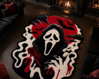 Puede incluir: Una alfombra ovalada con una ilustración gráfica de una figura enmascarada con túnica negra y capucha con manos blancas, sobre una gran luna roja, nubes negras y murciélagos volando, con gotas rojas que simulan sangre en el borde.