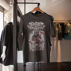 Könnte beinhalten: Schwarzes T-Shirt mit einem grafischen Druck eines Schädels, der einen Helm trägt und einen Hammer hält. Der Text "SLAVERY TO THE GRAVE" ist auf dem Shirt gedruckt.