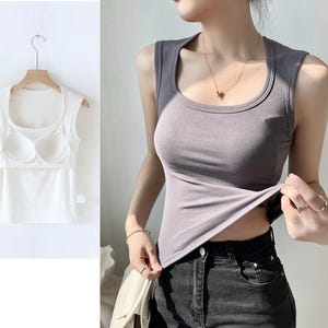 May include: A sleeveless tank top in a light purple color with a scoop neck. The tank top is made of a soft, stretchy fabric and has a relaxed fit.