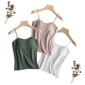 Puede incluir: Tres camisetas sin mangas de diferentes colores: verde, rosa y blanco. Las camisetas están hechas de una tela suave y elástica y tienen un diseño simple y clásico.
