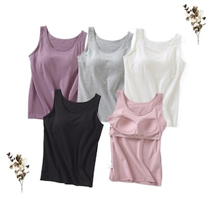 May include: Five tank tops in different colors: purple, gray, white, black, and pink. The pink tank top has a built-in bra.