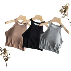 Puede incluir: Tres tops de halter en diferentes colores: marrón, negro y gris. Los tops están hechos de una tela suave y elástica y tienen un diseño simple y clásico.