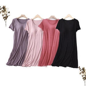 May include: Four sleeveless nightgowns hanging on hangers. The nightgowns are in shades of purple, pink, red, and black.