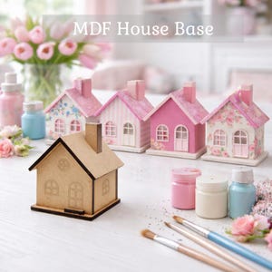 May include: An MDF house base and several miniature painted houses in pink hues. The houses have decorative details and glittered roofs. Paint bottles and brushes are arranged nearby, with the text "MDF House Base" at the top.
