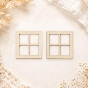 May include: Two square, light-coloured wooden window frame cutouts. Each piece features a simple, four-pane grid design with a flat, smooth surface. The frames are identical in shape and size, showcasing a natural, unfinished wood grain texture.