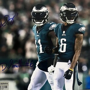 Puede incluir: Dos jugadores de fútbol americano con uniformes verdes y blancos, usando cascos. Uno tiene el número 11, el otro el número 6. La imagen está firmada con tinta azul. El fondo está borroso.