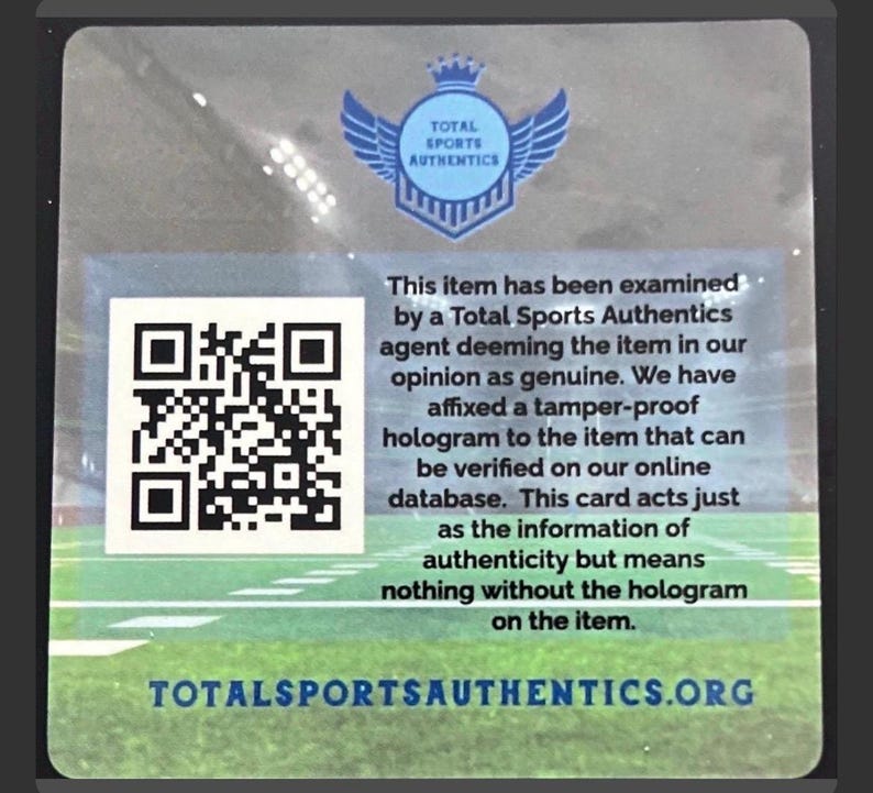 May include: A square authentication card featuring a Total Sports Authentics logo with wings and a crown, a QR code, and text stating the item has been examined and deemed genuine. The background shows a blurred stadium field, with the website URL at the bottom.