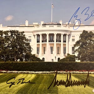 May include: Photograph of the White House with a fountain in front. The building is white with a flag on top. Two signatures are visible in blue and black ink. The lawn is green with a well-manicured appearance.