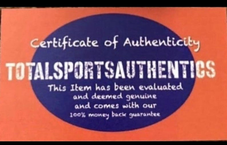 Może przedstawiać: Pomarańczowo-niebieski certyfikat z napisem "Certificate of Authenticity" i "TOTALSPORTSAUTHENTICS". Tekst potwierdza autentyczność przedmiotu i zawiera 100% gwarancję zwrotu pieniędzy.