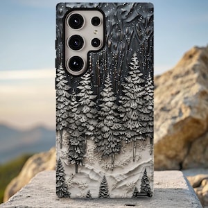 May include: A phone case with a 3D forest design. The case depicts a winter scene with snow-covered pine trees in shades of grey and white. The background is dark grey, and the surface has a textured finish.