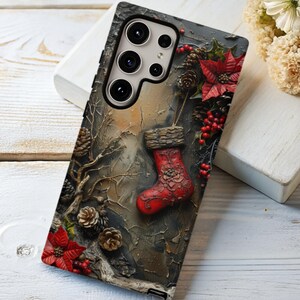 May include: A phone case with a Christmas theme. The case features a red stocking, pine cones, red berries, and poinsettias against a textured background. The case is designed to fit a smartphone with multiple camera lenses.