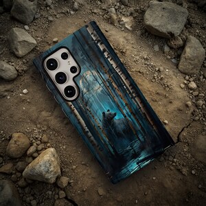May include: A phone case with a blue and white design featuring a bear in a forest. The case has a camera lens cutout and a textured surface.