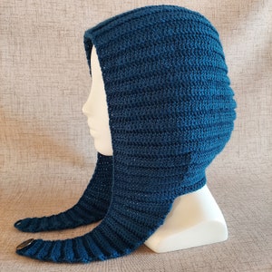 May include: A dark blue crocheted hooded hat with a long scarf attached. The hat is made with a ribbed stitch and has a simple design.
