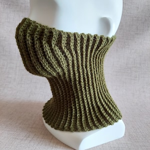 May include: A green crocheted neck warmer with a ribbed texture. The neck warmer is displayed on a white mannequin.