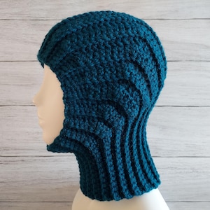 Peut inclure: Chapeau en crochet bleu sarcelle avec un cache-cou. Le chapeau a un rabat qui couvre le visage.