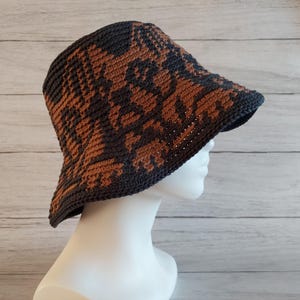 May include: A brown and black crocheted bucket hat with a floral pattern.