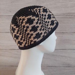 May include: A black and beige crocheted beanie with a geometric pattern.