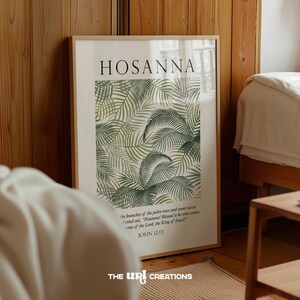 Puede incluir: Una impresión enmarcada con un diseño de hojas tropicales verdes y blancas. La impresión presenta el texto "HOSANNA!" y un versículo bíblico de Juan 12:13. La impresión está enmarcada en un marco de madera claro.