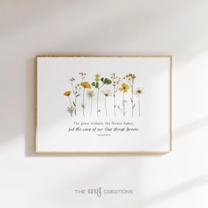 May include: A framed print featuring a collection of dried wildflowers in shades of yellow, white, and green. The print includes the text "The grass withers, the flower fades; but the word of our God stands forever." The bottom right corner has the text "THE URI CREATIONS."
