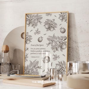 Puede incluir: Una impresión enmarcada con fondo blanco y una ilustración en blanco y negro de un árbol de cítricos con frutos. El texto "Fruit of the Spirit" está impreso en negro con una lista de cualidades, seguido de "Galatians 5:22-23".