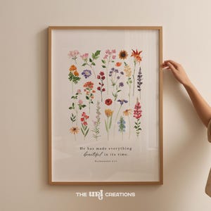 Może przedstawiać: Oprawiony wydruk z kolorowymi dzikimi kwiatami w odcieniach różu, pomarańczy, fioletu i żółci. Wydruk zawiera tekst "He has made everything beautiful in its time." i "Eklezjastes 3:11."