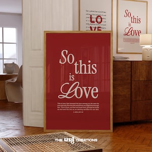 May include: A red framed print with white text that reads "So this is Love." The text is in a large, bold font. Below the text is a smaller quote from the Bible, 1 John 4:9-10, in a white font. The print is on a red background.